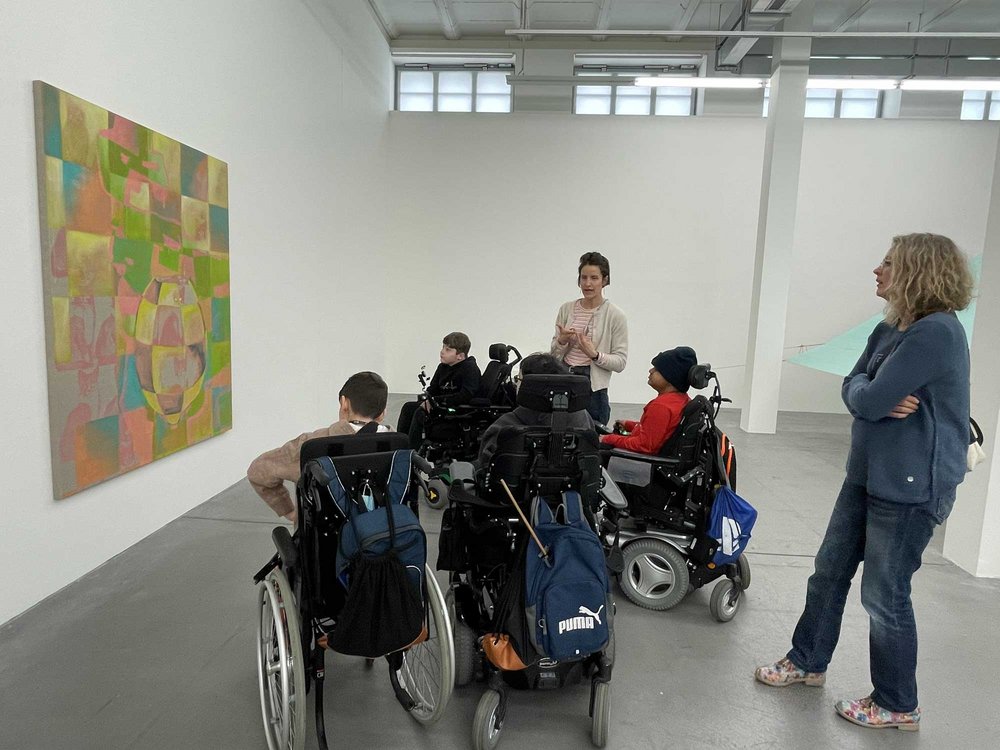 Eine Gruppe Jugendlicher in Rollstühlen bei einer Museumsführung.